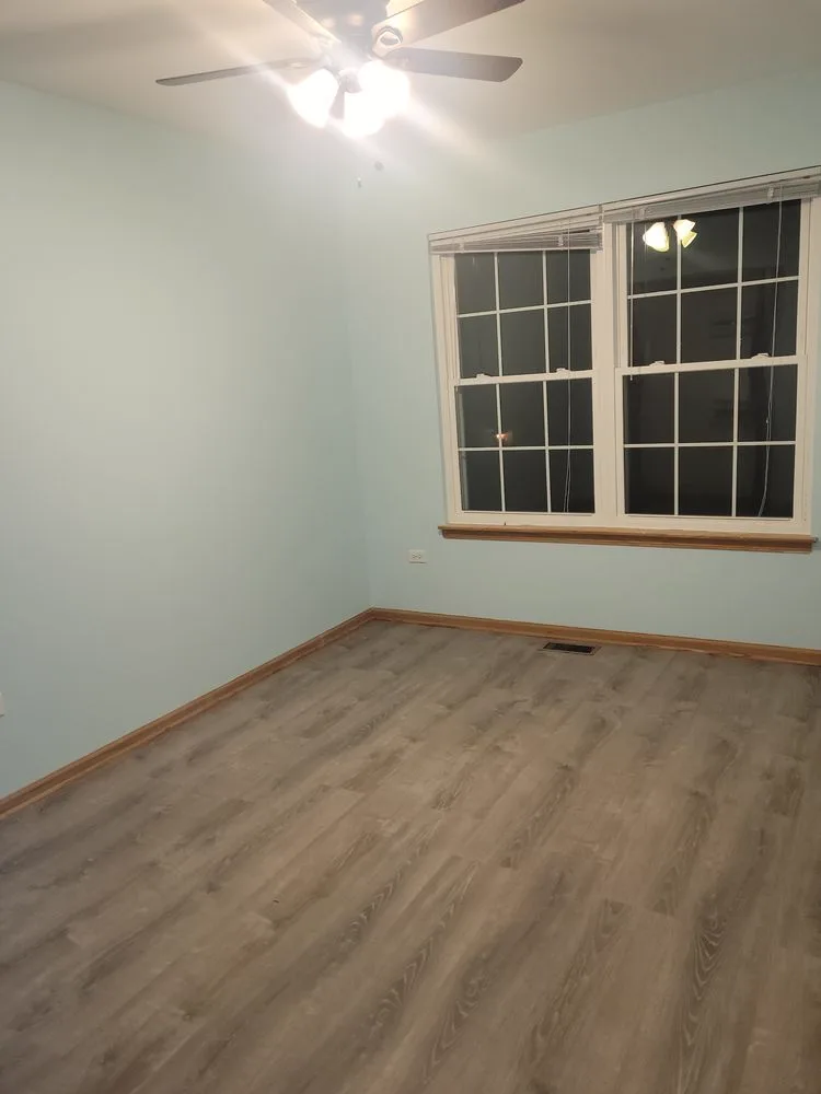 Freshly painted light-gray walls with a paint roller resting in the room